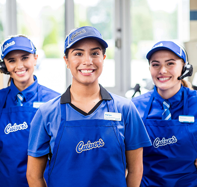 Three employees wearing blue aprons and caps